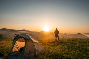 man staat voor zijn tent in de bergen als een illustratie bij een blog over vakantiegeld storten in je pensioen