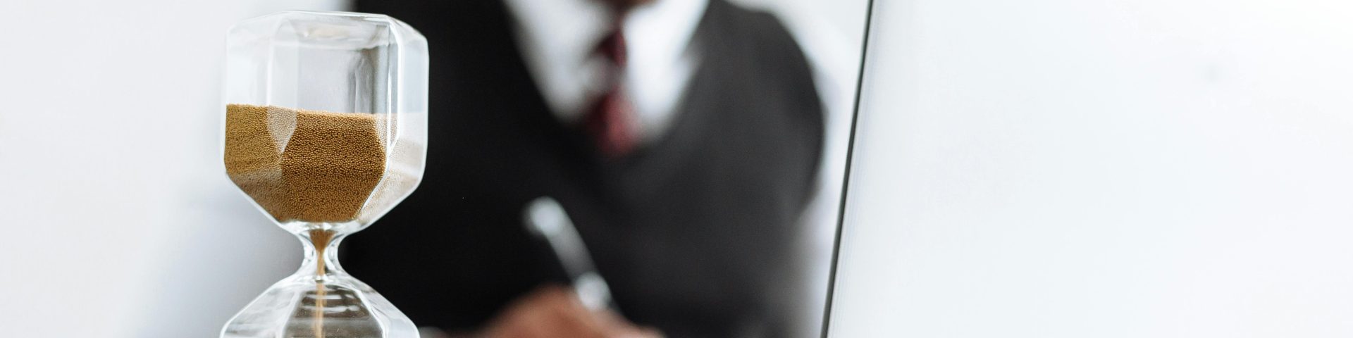 man zit achter een computer met daarvoor een zandloper bij een blog over pensioenplanning