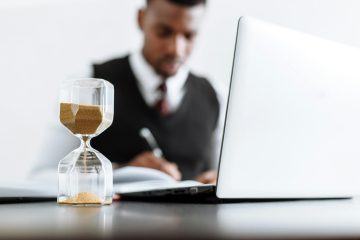 man zit achter een computer met daarvoor een zandloper bij een blog over pensioenplanning
