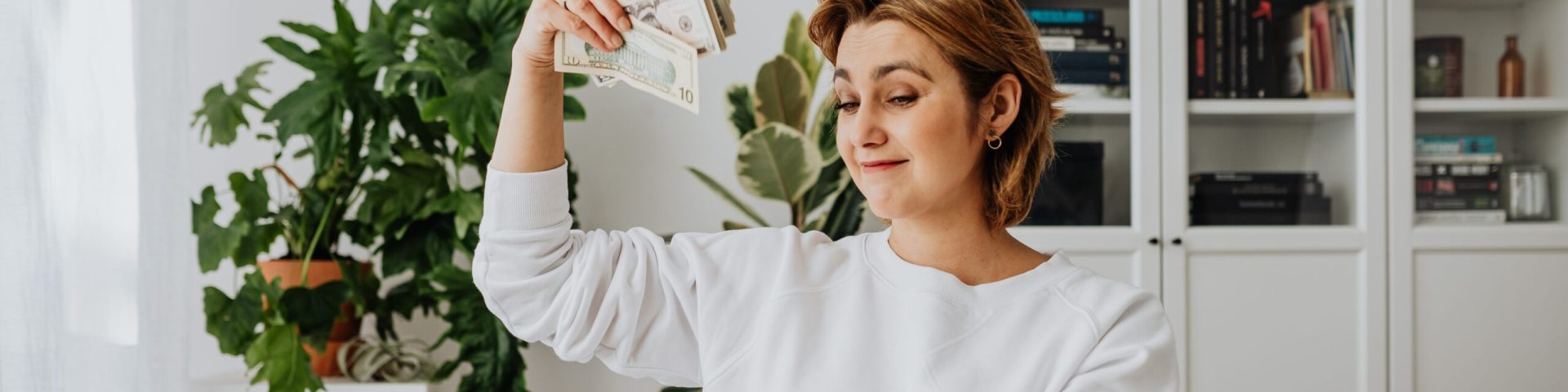 Vrouw achter laptop met geld in hand bij lijfrente en sparen