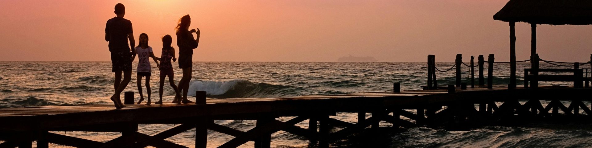 gezin op een pier in zee bij ondergaande zon als illustratie bij een blog over als je overlijdt, vervalt je pensioenpot