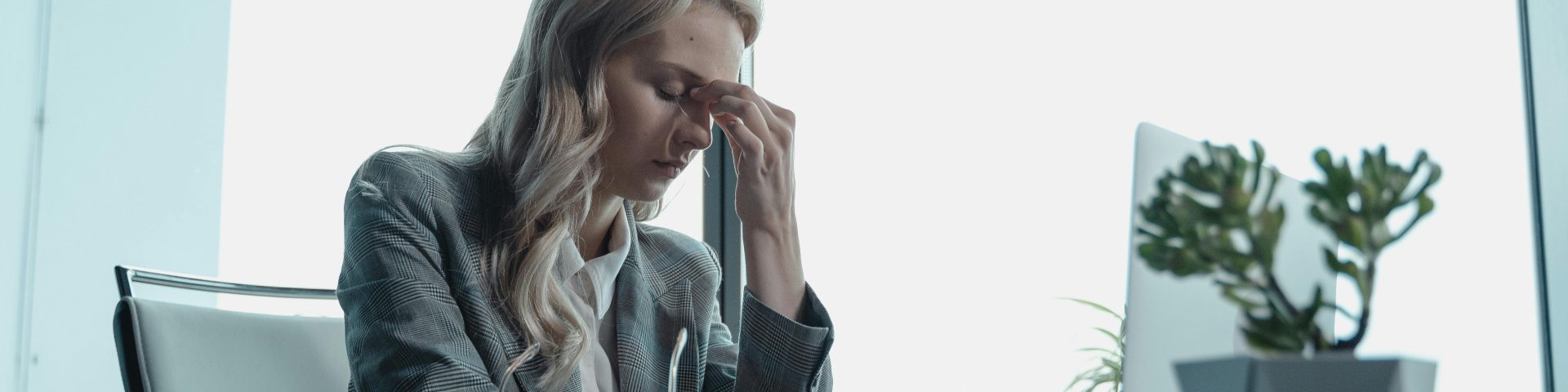 Een vrouw zit achter haar computer en kijkt bezorgd omdat het pensioen niet op tijd is aangepast